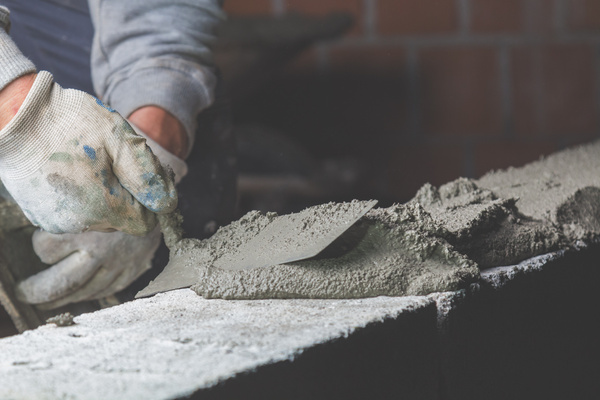 Bricklayer applying mortar to masonry blocks